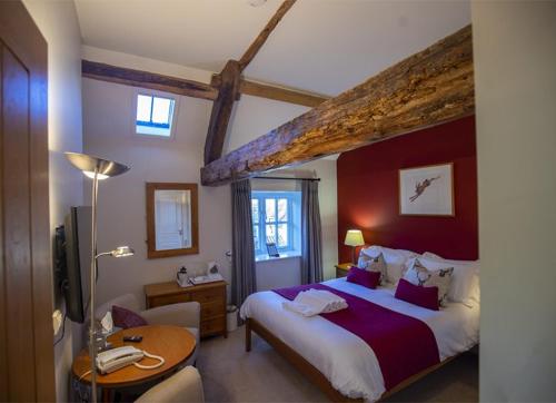 a hotel room with a large bed and a table at The Old Coach House in Ripon