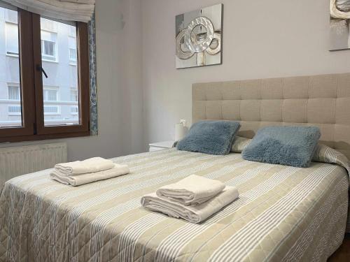 una camera da letto con un letto e asciugamani di Paxarinos Playa by FlowHome a Gijón