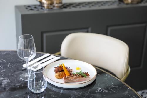 a plate of food on a table with a wine glass at Séquoias Golf & Ressort in Ruy