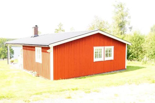 a red shed with a white window in a yard at Stuga med sjöutsikt. in Ingatorp