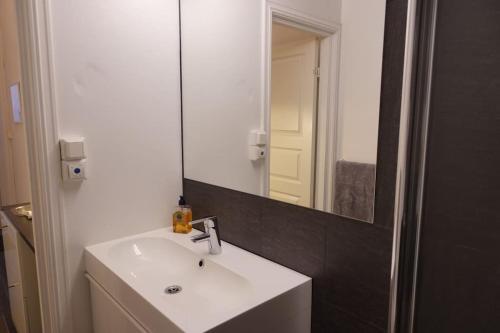 a bathroom with a white sink and a mirror at Just behind The Royal Palace in Oslo
