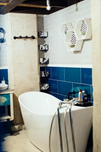 a bathroom with a white tub and blue tiles at RedCity LOFT 129 in Żyrardów