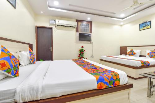 a bedroom with two beds and a desk at Hotel Pink Cozzy in Jaipur