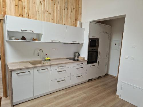 a kitchen with white cabinets and a sink and a refrigerator at Villa Garden in Bešeňová