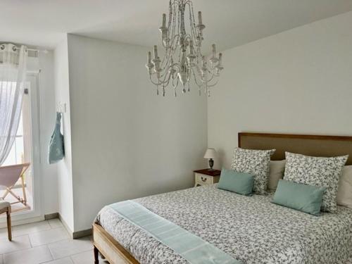 Schlafzimmer mit einem Bett und einem Kronleuchter in der Unterkunft Le Bleu Mer in Sète