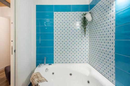 y baño con bañera y azulejos azules. en Rega Holiday House, en Nápoles