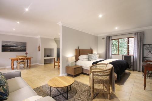 a bedroom with a bed and a living room at Stony Brook Cottages in Franschhoek