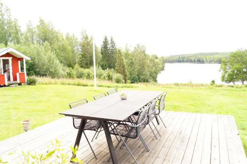 a picnic table on a deck with a view of a lake at Stuga med sjöutsikt. in Ingatorp