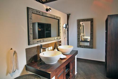 a bathroom with two sinks and two mirrors at Puri Mangga Sea View Resort and Spa in Lovina