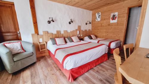 a bedroom with two beds and a chair and a table at Hôtel Le Sporting in Morzine