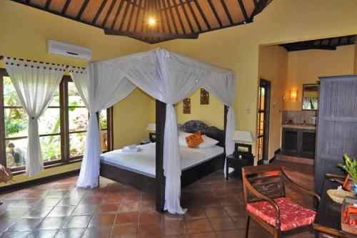 a bedroom with a bed with a canopy at Puri Mangga Sea View Resort and Spa in Lovina