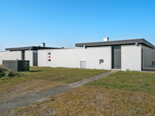 a white building in a field with a grass field at Apartment Tarvo - 500m from the sea in NW Jutland by Interhome in Pandrup
