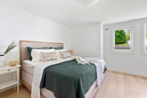 a white bedroom with a bed and a window at Exclusive apartment by the ocean in Tananger