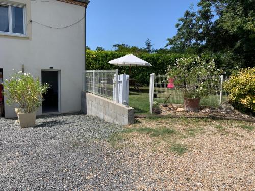 a fence with an umbrella next to a house at maison avec jardin et parking privé in Meschers-sur-Gironde