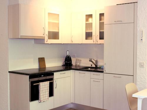 a white kitchen with white cabinets and a sink at Studio Les Dauphinelles by Interhome in Les Collons