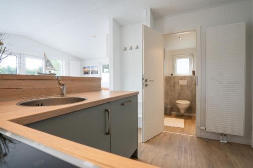 Il comprend une cuisine avec un lavabo et des toilettes. dans l'établissement Ostseecamp Lübecker Bucht Ferienhaus "Beachhouse" mit kostenlosen Saunazugang, à Scharbeutz