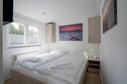 - un lit blanc dans une chambre avec fenêtre dans l'établissement Ostseecamp Lübecker Bucht Ferienhaus "Beachhouse" mit kostenlosen Saunazugang, à Scharbeutz