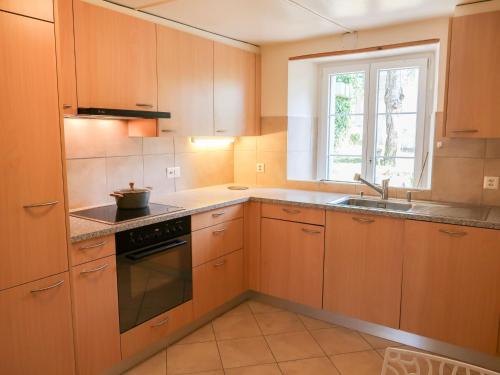 uma cozinha com armários de madeira, um lavatório e uma janela em Apartment Petit nid de Pully by Interhome em Cully