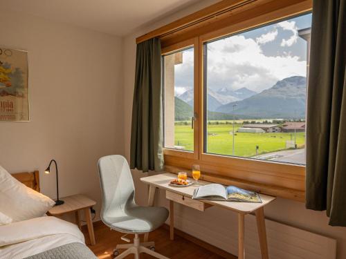 a bedroom with a desk and a window with a view at Apartment Chesa Muntarütsch by Interhome in Samedan