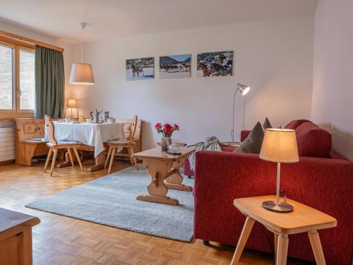 ein Wohnzimmer mit einem roten Sofa und einem Tisch in der Unterkunft Apartment Chesa Muntarütsch by Interhome in Samedan