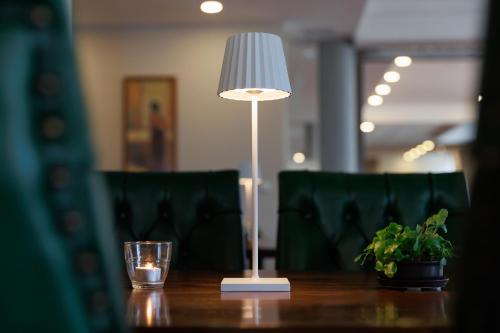 a lamp on a table with a glass and a plant at Darovanský Dvůr - Wellness & Golf Hotel in Břasy