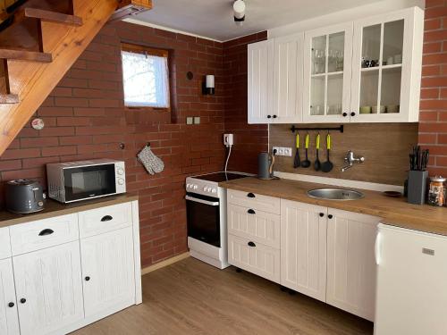 a kitchen with white cabinets and a brick wall at Holiday Home Jaruška by Interhome 
