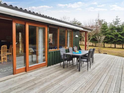a deck with a table and chairs on a house at Holiday Home Nada - 200m from the sea in Bornholm by Interhome in Vester Sømarken
