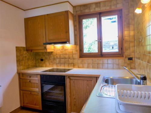 cocina con armarios de madera, fregadero y ventana en Holiday Home Moncalme by Interhome, en Crans-Montana