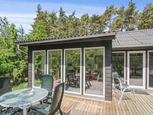 a screened in deck with a table and chairs at Holiday Home Gudmand - 600m from the sea in Bornholm by Interhome in Vester Sømarken