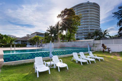un grupo de sillas blancas junto a una piscina en Baan Poolom Beachfront Condominium, en Hua Hin