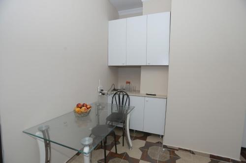 a white kitchen with a glass table and chairs at The K Tbilisi in Tbilisi City