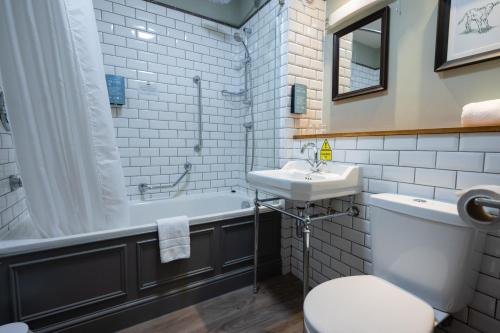 a bathroom with a sink and a tub and a toilet at St Leonards Hotel by Greene King Inns in Saint Leonards