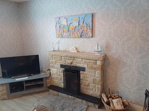 a living room with a fireplace and a television at Tirchonaill Townhouse in Donegal