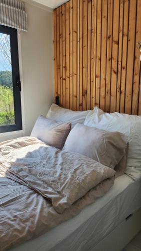 ein Bett mit weißer Bettwäsche und Kissen neben einem Fenster in der Unterkunft OFFGRID Haus am Angelteich 