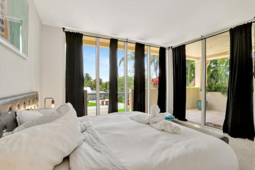 a white bed in a bedroom with a large window at Coastal Condo Deerfield Beach Retreat 3 bed 2 bath in Deerfield Beach