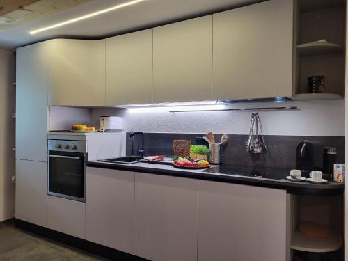 a kitchen with white cabinets and a black counter top at Holiday Home Cà dal Leo by Interhome in Bignasco