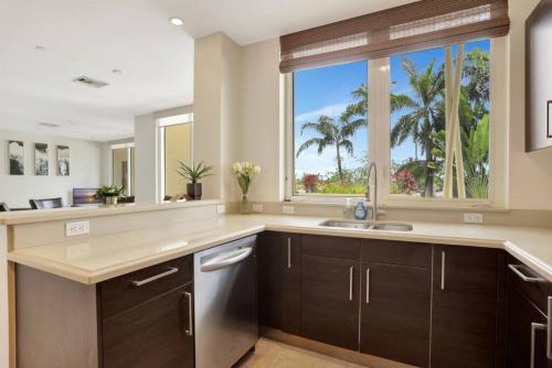 uma cozinha com um lavatório e uma janela com palmeiras em Coastal Condo Deerfield Beach Retreat 3 bed 2 bath em Deerfield Beach