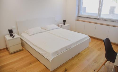 - une chambre avec un grand lit blanc et une chaise dans l'établissement Apartment White, à Šibenik
