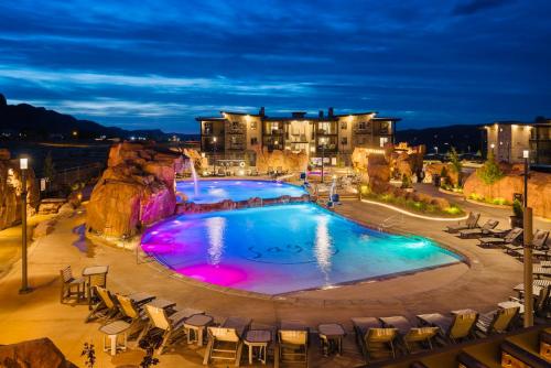 a large swimming pool with chairs around it at night at Sage Creek at Moab Luxury Condo B in Moab