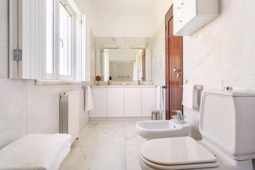 a white bathroom with a toilet and a sink at Casal das Aveleiras in Cartaxo