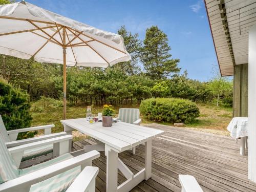 a white table and chairs with an umbrella on a deck at Holiday Home Sisko - 800m from the sea in Western Jutland by Interhome in Vejers Strand
