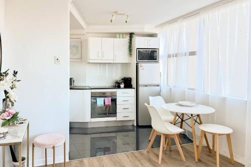 a kitchen with white cabinets and a table and chairs at Abwechslungsreiche Unterkunft mit charmanten Flair in Hilden