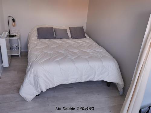 1 cama con sábanas blancas y almohadas en una habitación en Appartement Côte Fleurie - MERVILLE FRANCEVILLE PLAGE, en Merville-Franceville-Plage