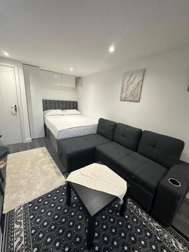 uma sala de estar com um sofá e uma cama em Centrally located private studio flat in Luton em Luton