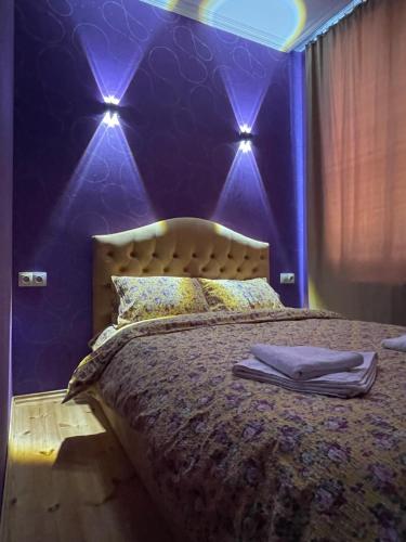 Sunny guesthouse في كازباجي: غرفة نوم مع سرير والجدران الأرجوانية والأضواء