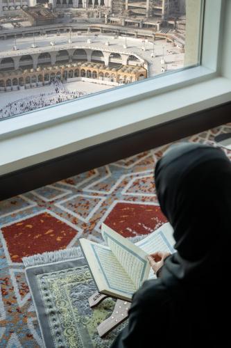 a person sitting in front of a window with a laptop at Swissotel Makkah in Makkah