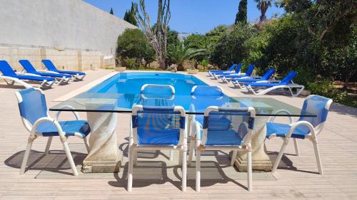 Un grupo de sillas y una mesa y una piscina. en Stunning Villa with Pool, Table tennis, Table soccer and a Pool table, en Naxxar