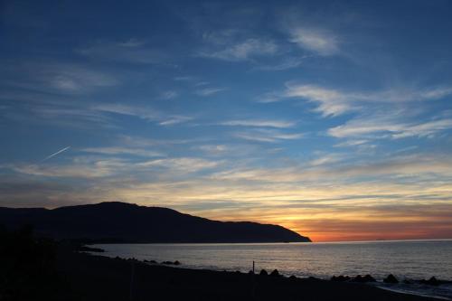 a sunset on a beach with a mountain in the background at Medimare Residence Club in Patti