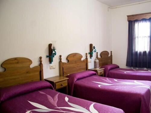 a room with three beds with purple sheets at APARTAMENTOS SIETE LAGUNAS in Trevélez