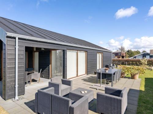 un patio avec une table et des chaises et un plan de travail table et chaises dans l'établissement Holiday Home Aaran - 700m from the sea in NW Jutland by Interhome, à Blokhus
